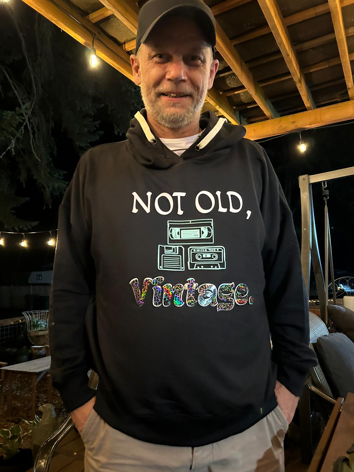 "Not Old, Vintage" hoodie with vintage video cassette, audio tape, and floppy disk on male model.